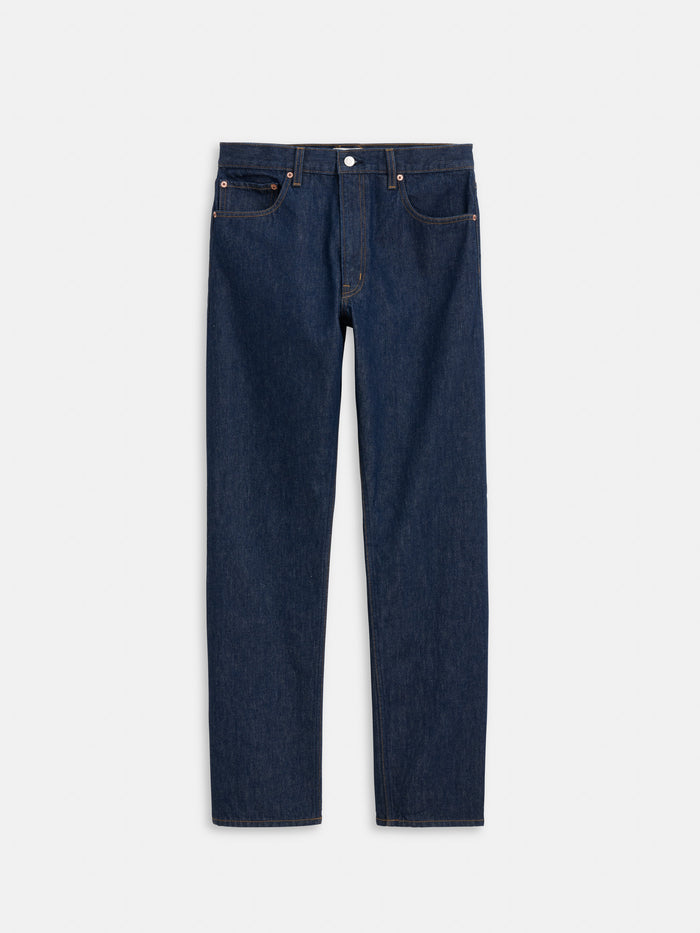 The AM Original 5 Pocket Jean X J.Press is a men's straight-leg blue jean made from 100% cotton, featuring five pockets and a button closure, shown flat on a white background.