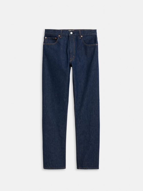 The AM Original 5 Pocket Jean X J.Press is a men's straight-leg blue jean made from 100% cotton, featuring five pockets and a button closure, shown flat on a white background.