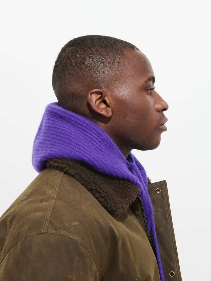 A person in profile wears a brown shearling jacket and a thick, ribbed Balaclava in Cashmere against a plain white background.