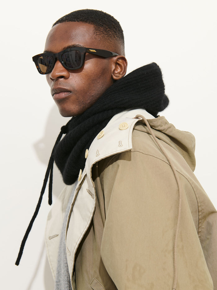 A man wearing black sunglasses, a khaki hooded jacket, and the Balaclava in Cashmere stands against a plain white background.