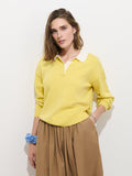 A woman with shoulder-length brown hair wears the Bond St Polo In Cotton Cashmere in yellow, styled in a relaxed fit with a tan skirt, silver bracelet, and blue scrunchie, standing against a plain white background.