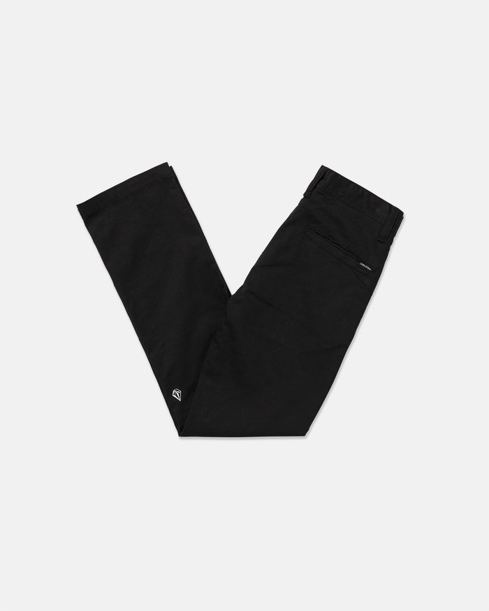 A pair of Volcom Kids' Big Boys' Frickin Modern Stretch Pants in black, folded in a "V" shape on a white background. Made with REPREVE recycled fibers, they feature a back zipper pocket and an embroidered logo near the ankle.