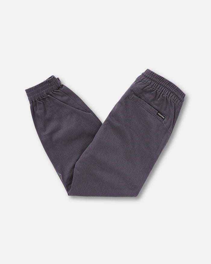 The Volcom Kids' Big Boys Frickin Slim Joggers, dark gray with an elastic waist and cuffs, made from recycled fibers, are folded in half and laid flat on a white background.
