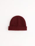 The Cashmere Beanie in maroon, featuring a folded brim and knitted construction, is displayed flat on a white background.