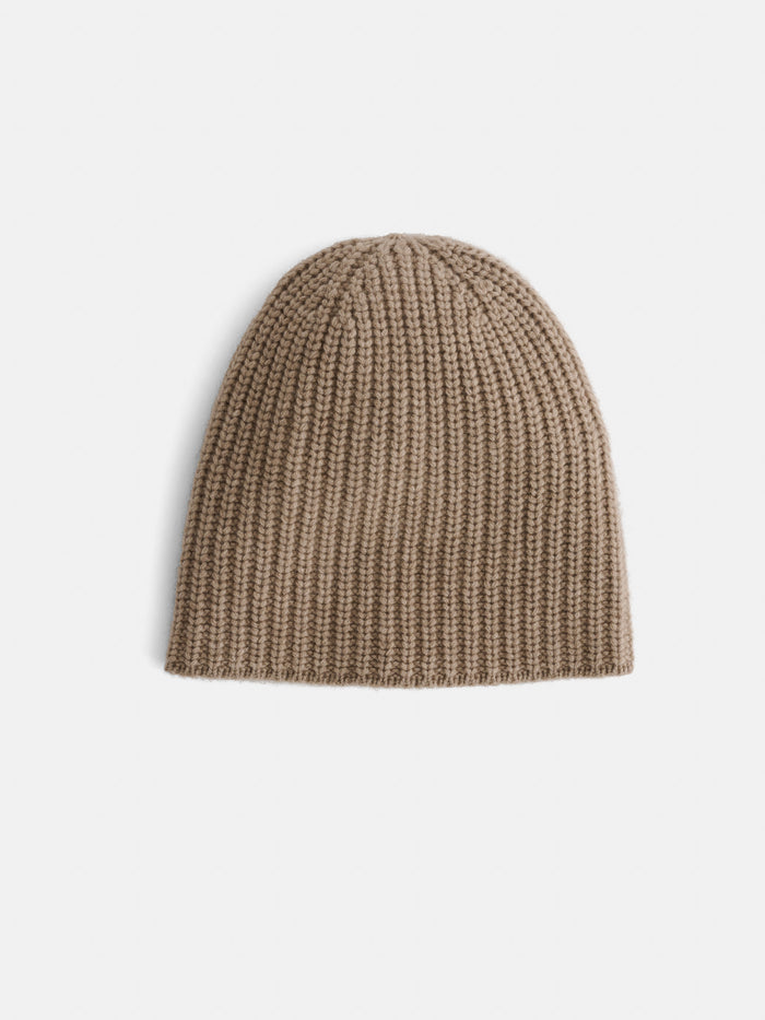 The Cashmere Beanie, featuring a beige ribbed knit design, is shown against a plain white background to emphasize its soft texture and cozy warmth.