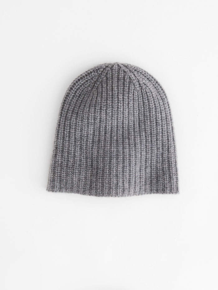 The Cashmere Beanie is pictured laid flat on a white background, highlighting its gray ribbed knit and ultraluxurious, supersoft texture in a warm beanie style.