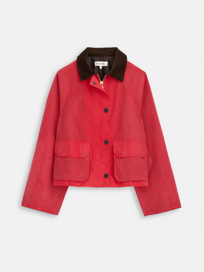 The Chiltern Cropped Jacket in Waxed Canvas features a vibrant red finish, wide sleeves, black buttons, two large front pockets, and a dark brown corduroy collar—a vintage-inspired, water-resistant statement piece shown on a white background.