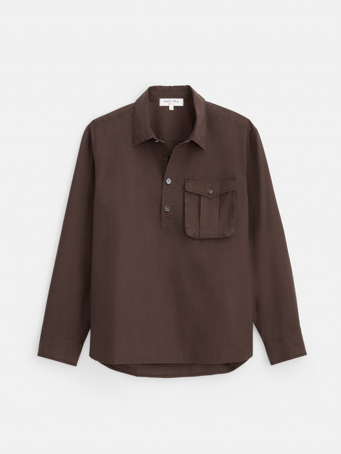 The Clint Popover in Cotton Poplin is a men’s long-sleeve shirt in dark brown, garment-dyed cotton, designed with a collar, partial button placket for a classic popover style, and a single chest pocket—shown against a plain white background.