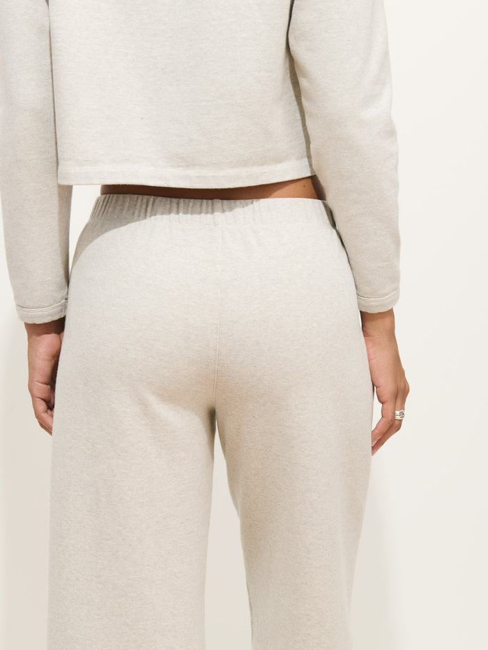 A woman is seen from the back wearing a light gray, long-sleeve top and matching Coco Sport Pant in cotton double jersey—a refined look that defines women's designer style. Her right hand rests by her side.