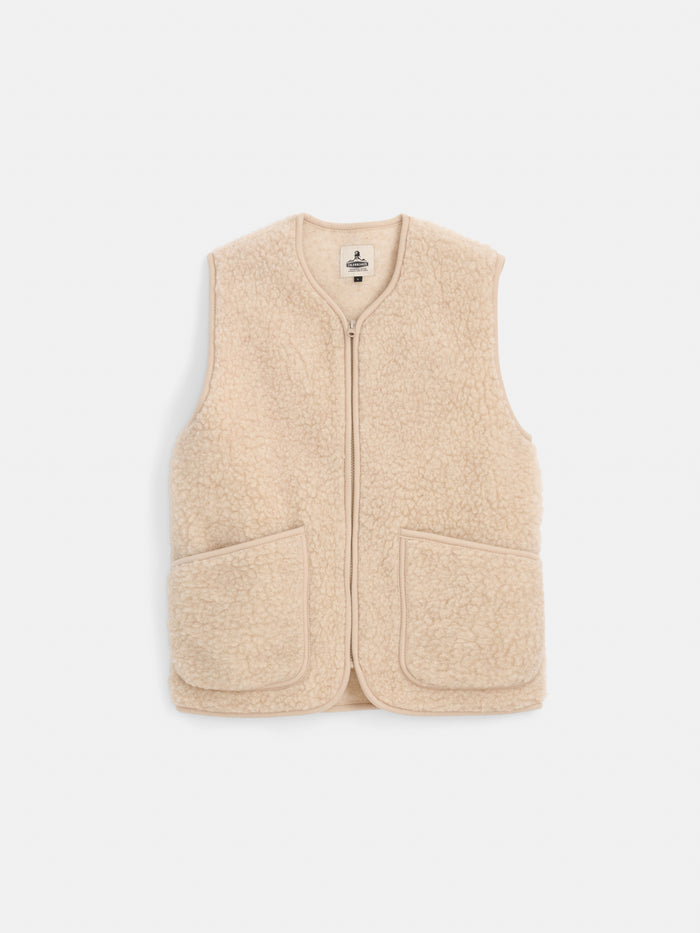 The Coldbreaker Standard Vest is a beige, sleeveless fleece vest made from 100% Irish wool with a front zipper and two large front pockets. Unisex sizing ensures it fits everyone, displayed here against a plain white background.