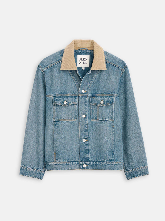 The Denim Jacket features a vintage-inspired unisex design with silver buttons, front chest pockets, and a tan corduroy collar. The inner label reads Alex Mill. It is displayed laid flat against a light background.
