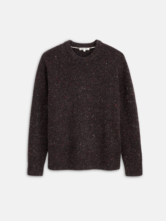 The Donegal Crewneck Sweater, shown in dark brown with long sleeves and a textured speckled pattern, is laid flat on a light gray background.