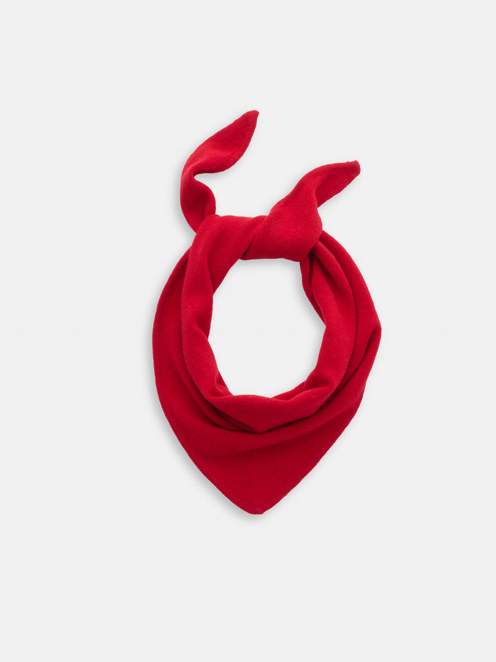The Flynn Handkerchief Scarf in Wool, featuring a vibrant red color and pointed ends, is tied loosely in a knot and displayed against a plain white background.