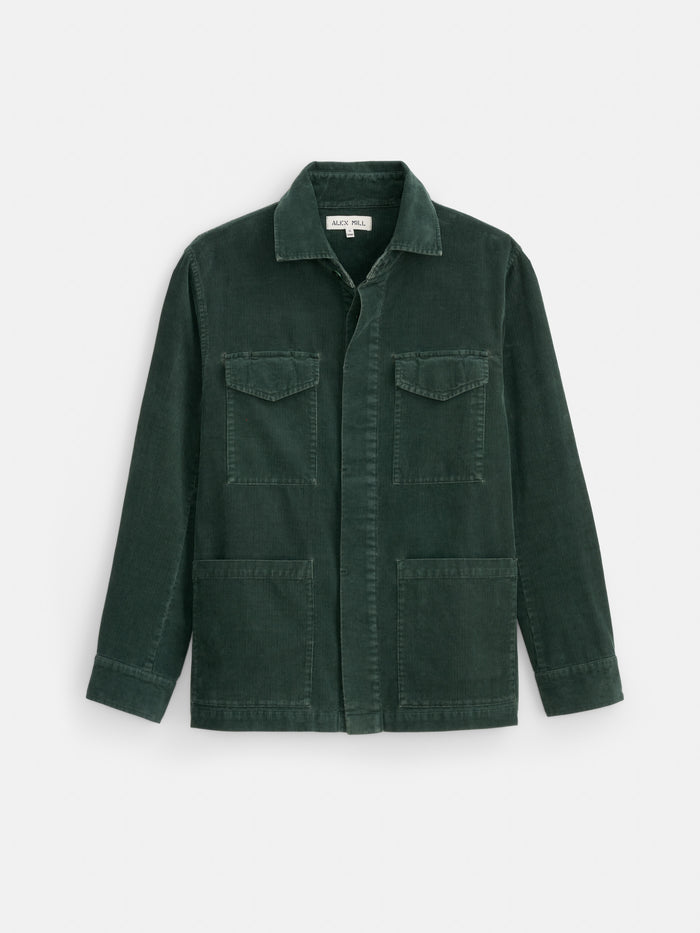 The Garment Dyed Chore Jacket in Corduroy is shown in dark green on a white background, featuring long sleeves, a collar, two chest flap pockets, two lower front pockets, and a button-down front with corozo buttons.
