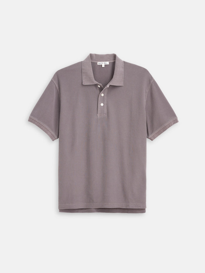 The Garment Dyed Polo In Pique Cotton features short sleeves, a collar, and three buttons down the front in light purple-gray, displayed on a plain white background.