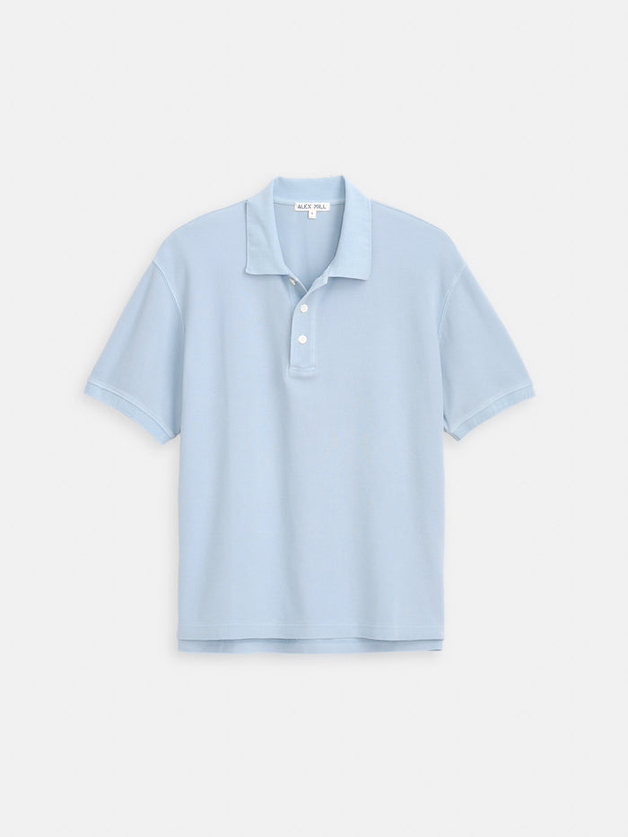 The Garment Dyed Polo In Pique Cotton is a light blue, 100% cotton short-sleeve shirt with a collar and three white buttons, shown against a plain white background.