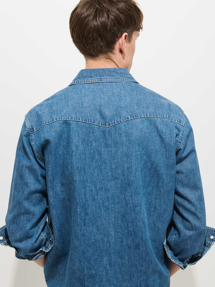 A person with short brown hair is seen from behind, wearing the Jackson Pocket Shirt in Denim with rolled-up sleeves against a plain white background.