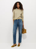 A woman with curly hair wears a gray and yellow striped sweater, the Jane Mid-Rise Straight Jean crafted from 100% cotton denim, and yellow flats. She holds a small brown bag and stands against a plain white background.