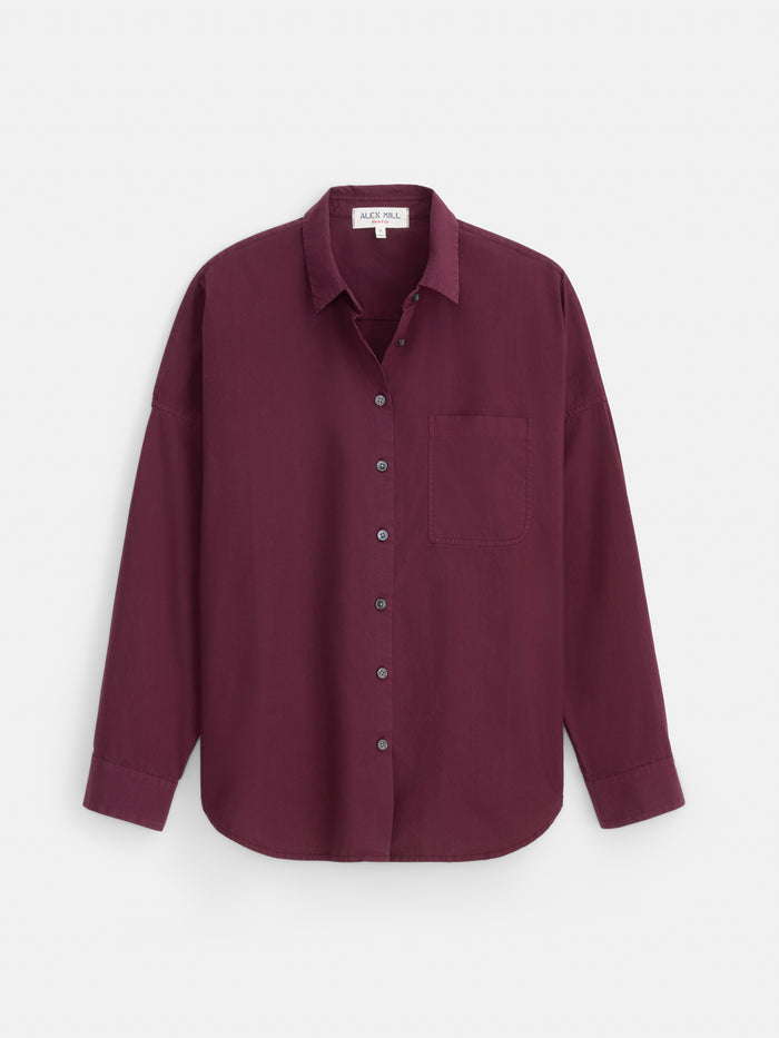 Introducing the Jo Shirt In Cotton Poplin: a long-sleeve, button-up shirt crafted from 100% cotton poplin in a rich burgundy hue. Finished with elegant Troca shell buttons and featuring a classic chest pocket, this timeless piece is shown against a white background.