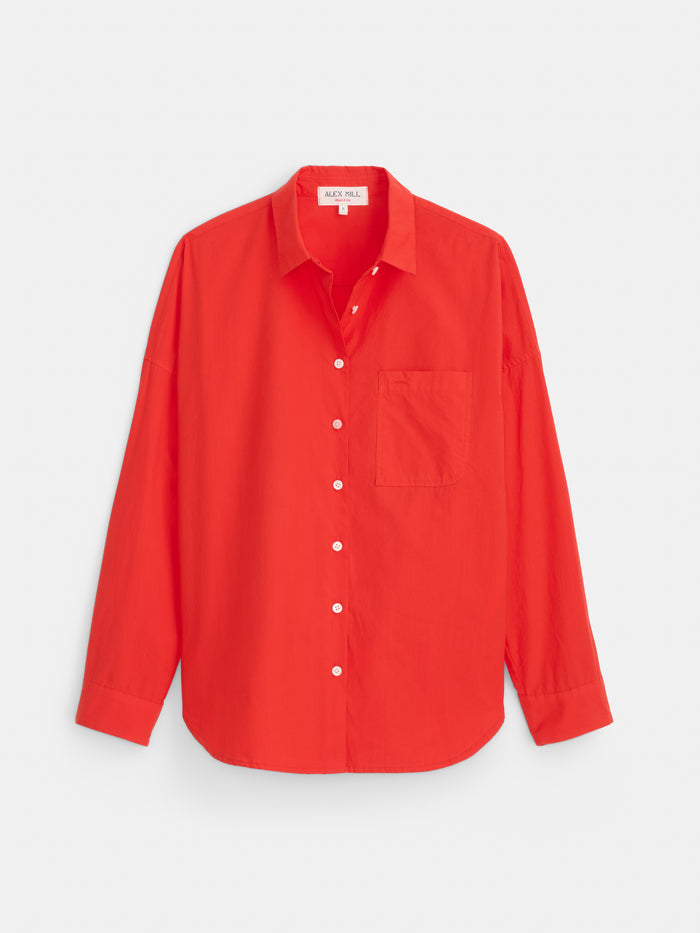 The Jo Shirt In Cotton Poplin, crafted from 100% cotton, features a bright red color, long sleeves, a collar, Troca shell buttons down the front, and a single chest pocket. The shirt is laid flat on a plain white background.