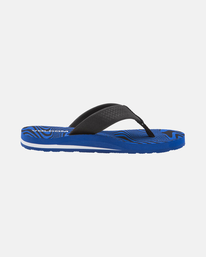 The Volcom Kids' Daycation 2 Big Youth sandal features a single blue design with a textured black strap, blue sole with black and white wavy patterns, and built-in arch support for comfort, shown on a plain white background.