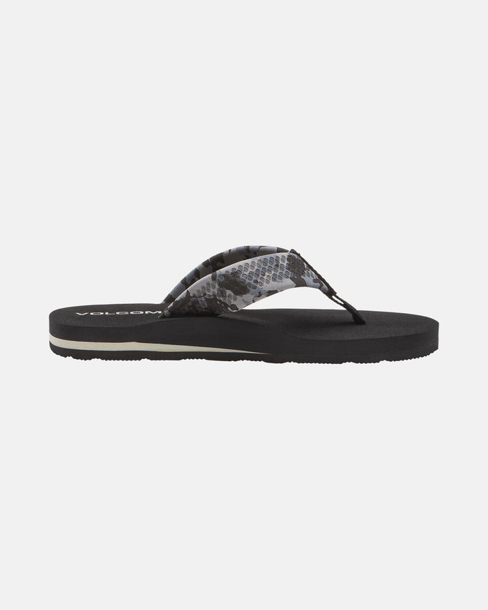 The Volcom Kids' Daycation 2 Big Youth sandal features a flat sole, cushioned Recliner Comfort Foam, and a black translucent strap with a gray snake-like pattern. The Volcom logo is partially visible on the footbed near the heel.