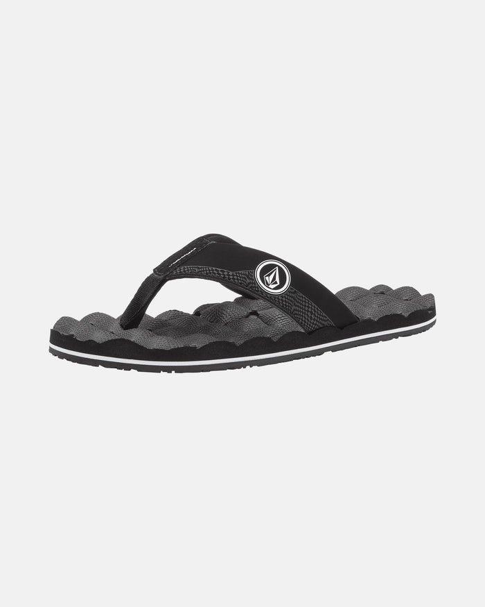 The Volcom Kids' Recliner 2 Big Youth sandal features a black and gray design, wavy textured sole, black fabric strap with a round side logo, and a comfort foam footbed. Shown on a plain white background.