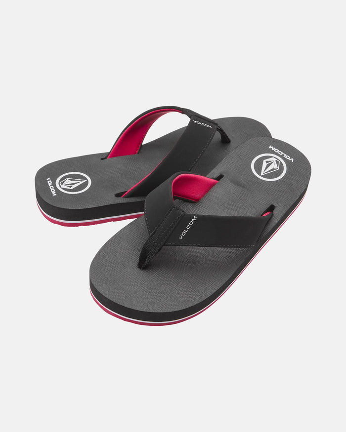 The Volcom Kids' Victor 2 Big Youth sandals are black flip-flops with pink accents and the Volcom logo on the heel and footbed, offering recliner-level comfort, shown on a white background.