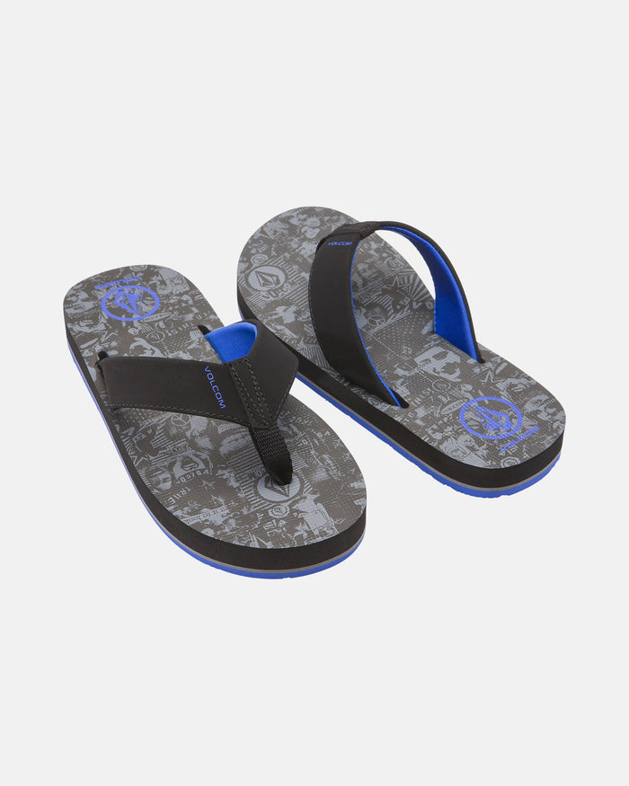 The Volcom Kids' Victor 2 Big Youth flip-flops feature black and blue straps, patterned gray soles with graphic designs, non-scuff outsoles, and blue logo accents, shown against a plain white background.