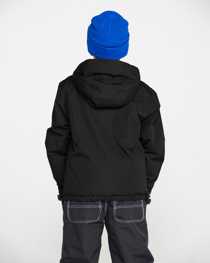 A person is seen from behind, standing against a plain white background, wearing a blue knit hat, dark pants with visible white stitching, and a black Volcom Kids’ Youth Chaos Insulated Jacket with recycled insulation.