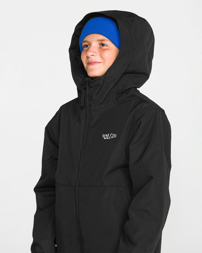 A person wears the Volcom Kids’ Youth Chaos Insulated Jacket in black, featuring recycled insulation and the VOLCOM logo on the chest, paired with a bright blue beanie. They smile slightly against a plain white background, showcasing this reliably weather-resistant outerwear.
