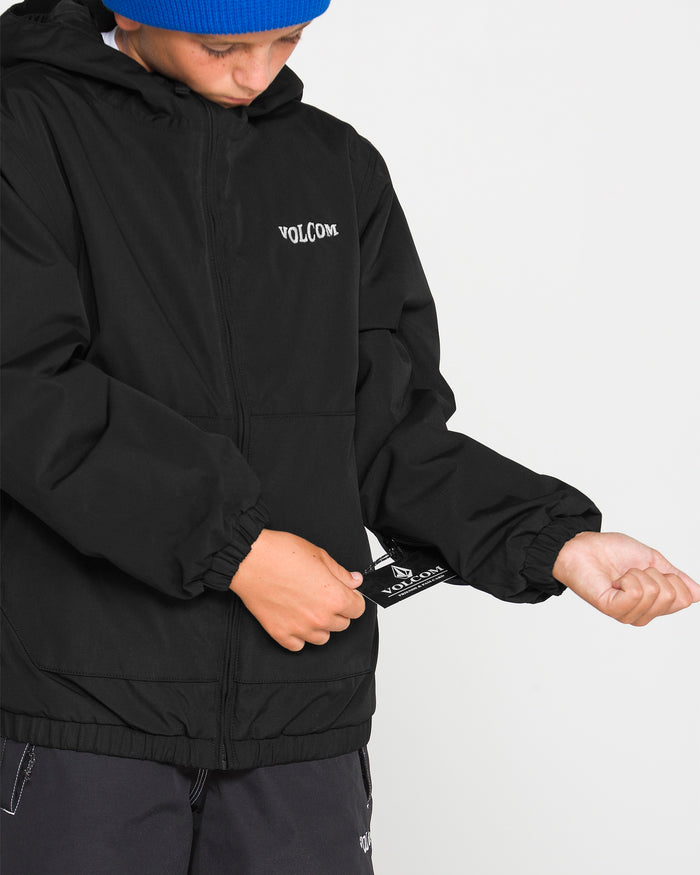 A person in a blue beanie and black Volcom Kids’ Youth Chaos Insulated Jacket tugs on a tag inside the jacket sleeve. Only their lower face and torso are visible, highlighting the weather defense technology and recycled insulation of this stylish outerwear.