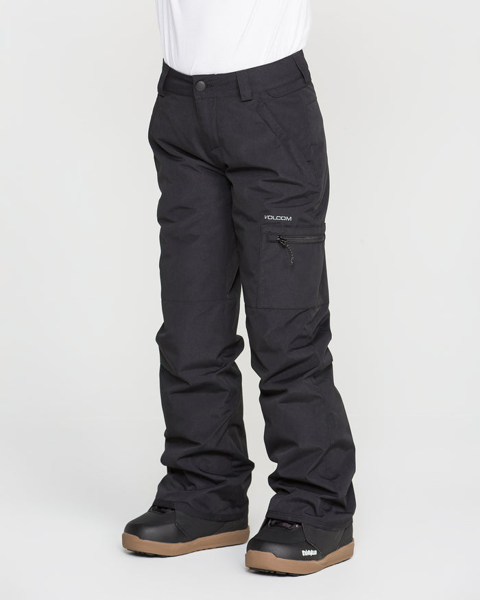 A person is wearing black Volcom Kids’ Frostique Insulated Pants, featuring an adjustable waist, along with black snow boots with brown soles. The image shows only the lower half of the body against a plain white background.