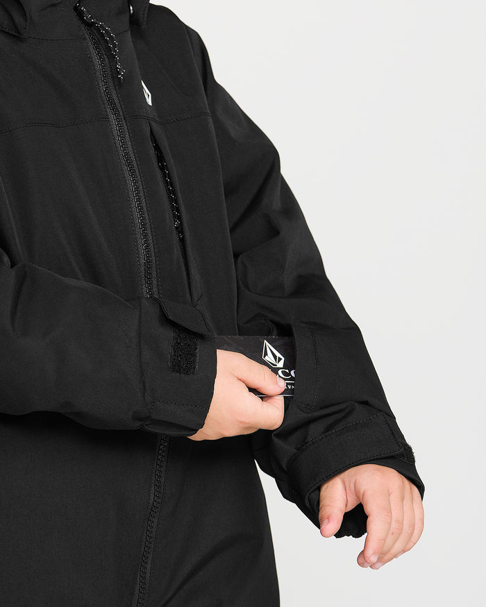 A person adjusts the Velcro cuff of a Volcom Kids’ Little Flurry One Piece Snow Suit sleeve, with only their hands and part of the suit visible against a light background.