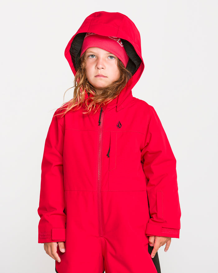 A child with long hair stands against a plain white background, wearing the Volcom Kids’ Little Flurry One Piece in bright red, crafted from recycled V-Science material.