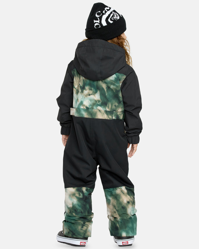 A child faces away, wearing the Kids' Little Flurry One Piece in black and green tie-dye, a black beanie with white lettering, and black-and-white sneakers, against a plain light background.
