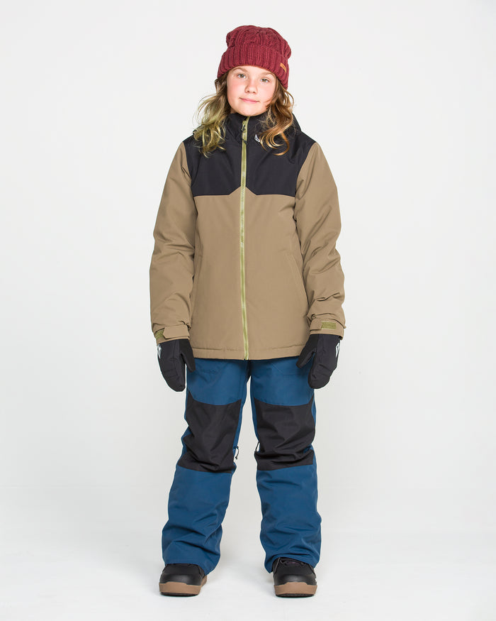 A person is wearing a red beanie, tan and black jacket with recycled insulation, black gloves, and Volcom Kids’ Youth Barkley Insulated Bib blue snow pants, standing facing forward against a plain white background.
