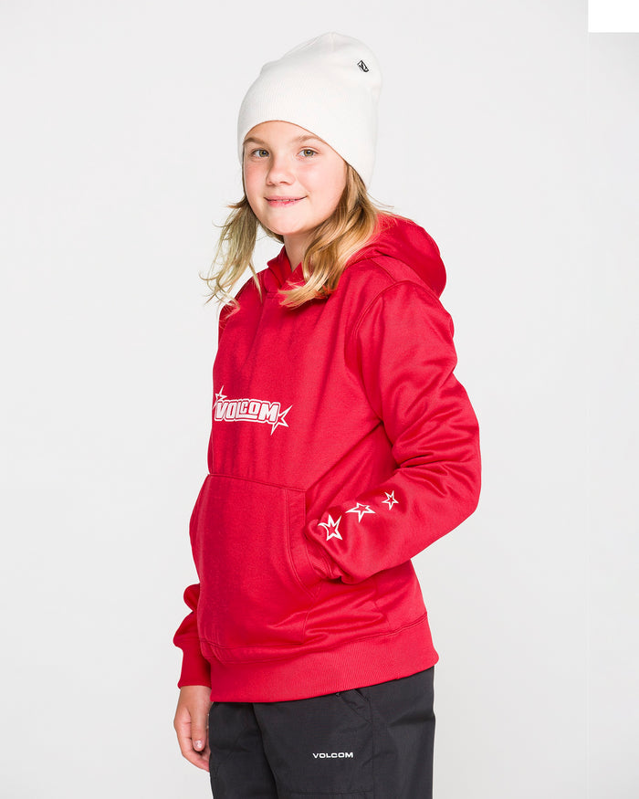 A young person in a red Volcom Kids’ Youth Hydro Fleece Hoodie, featuring star designs on the sleeve and a convenient handwarmer pocket, pairs it with black pants and a white beanie while standing against a plain white background and smiling slightly at the camera. The hoodie is made from hydrophobic fleece for extra comfort.