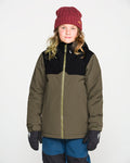 A child wearing a maroon knit beanie, black gloves, blue pants, and the Volcom Kids’ Youth Stone.91 Insulated Jacket in an olive and black colorway with recycled insulation stands facing forward against a plain white background.
