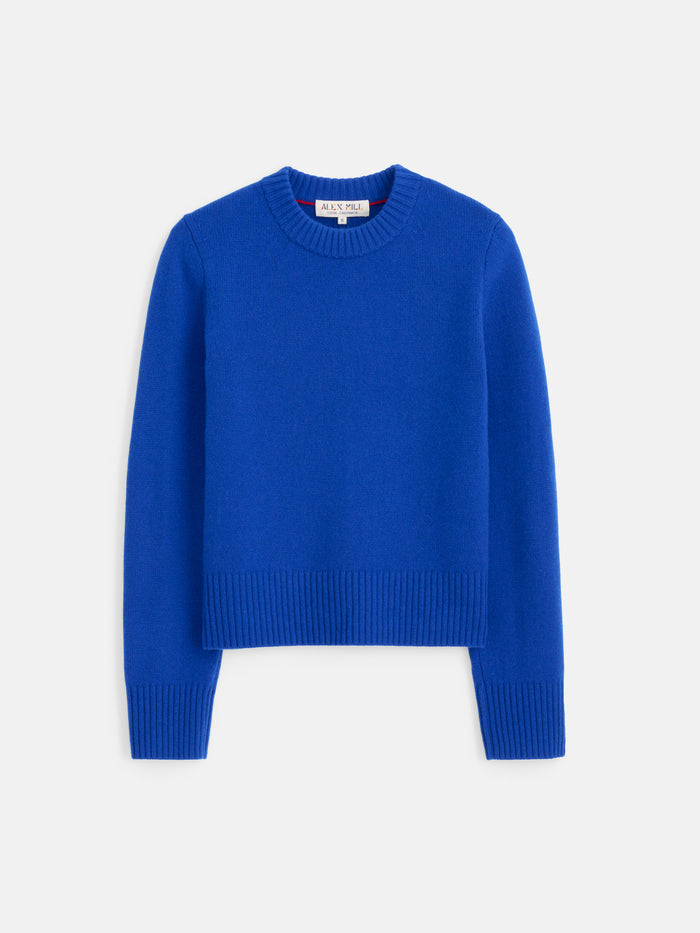 The Marais Sweater in Washed Cashmere, shown laid flat on a white background, is a bright blue luxury crew neck with long sleeves and ribbed cuffs, collar, and hem, crafted from 100% cashmere for exceptional softness.