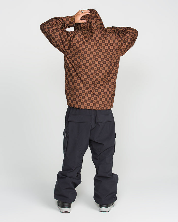 Facing away from the camera, the person wears Volcom’s Men’s 2836 Insulated Jacket in a brown pattern with the hood up, paired with black cargo pants and black sneakers. Against a plain white background, they raise their hands to touch the back of the hood, showcasing the jacket’s functional style featuring V-Science 2-Layer technology and 10K waterproof performance.