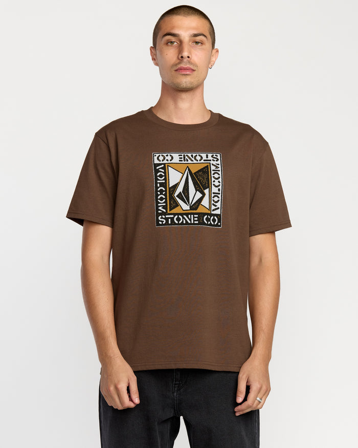 A man with short hair wears the Volcom Men's Angle Iron Short Sleeve Tee, featuring a bold geometric logo and "VOLCOM STONE CO." in a rectangular design, made from premium ring-spun cotton. He stands against a plain white background.