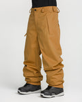 A person wearing loose-fitting tan Volcom Men’s Arthur 20K Pants, made from V-Science 2-Layer recycled twill, paired with black snow boots, stands against a plain white background with only the lower body visible.