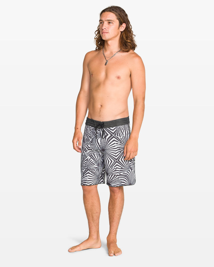 Man wearing black and white patterned swim shorts on a white background