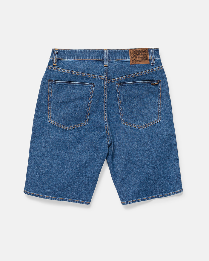 Back view of Volcom Men's Billow Denim Short 22 in blue, featuring two rear pockets and a brown leather patch on the waistband, laid flat on a white background.