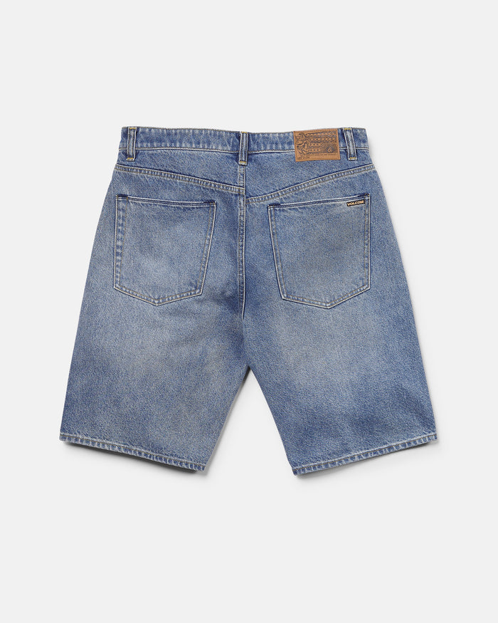 Back view of Volcom Men's Billow Denim Shorts in blue, featuring two large rear pockets, belt loops, and a brown leather patch on the waistband. These shorts offer a loose fit and a slightly faded look.
