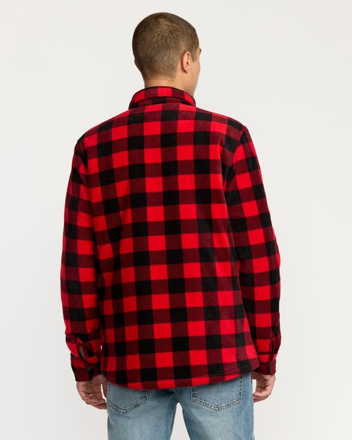 A person wearing the Volcom Men's Bowered Fleece Long Sleeve in a red and black checkered pattern with blue jeans stands facing away from the camera against a plain white background.