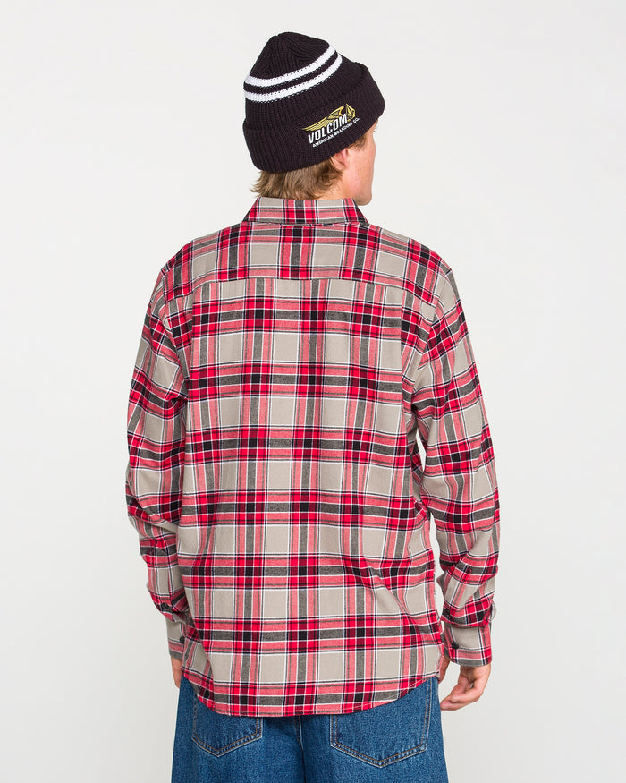 A person wearing a black beanie, blue jeans, and the Volcom Men's Caden Plaid Long Sleeve Shirt in a classic fit red and beige cotton plaid is standing with their back to the camera against a plain white background.