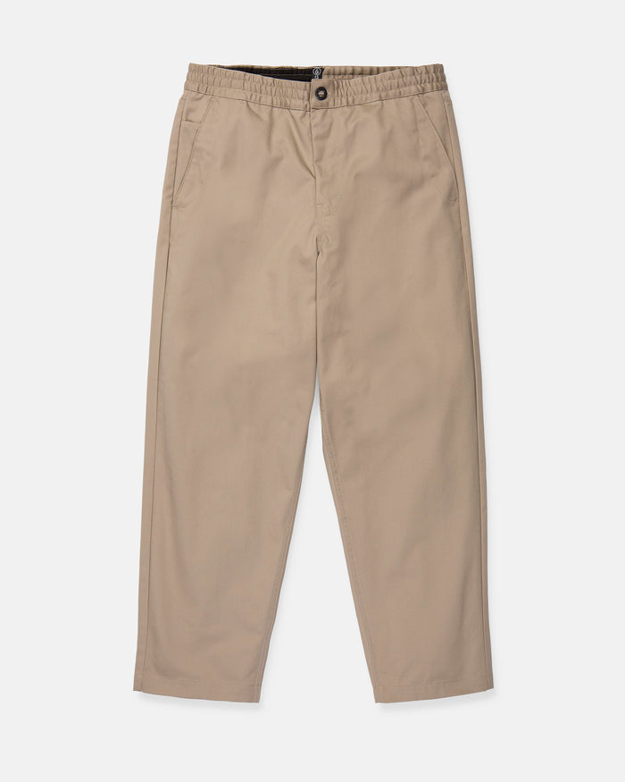 Volcom Men's Capreezy Elastic Waist Pants in beige khaki, featuring a button closure, straight legs, and crafted from pre-laundered twill, are shown laid flat on a white background.