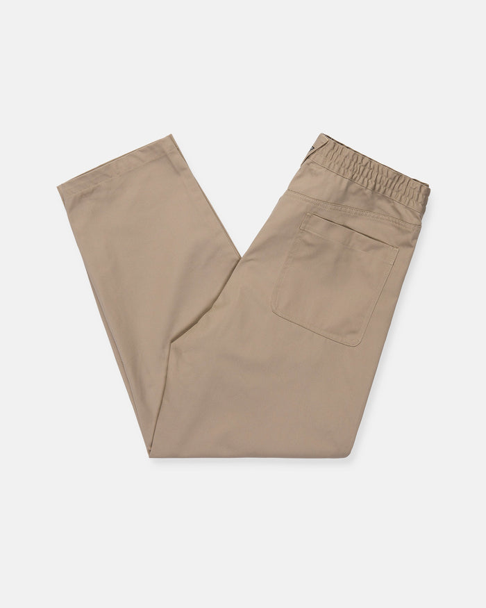 The Volcom Men's Capreezy Elastic Waist Pants in khaki are neatly folded to showcase their tapered leg and single back pocket, crafted from pre-laundered twill and set against a plain white background.